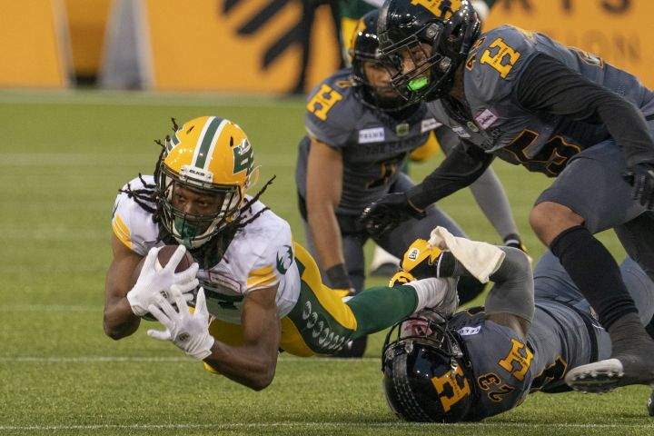 Edmonton Elks wide receiver Derel Walker (87) dives for yardage after being tackled by Hamilton Tiger Cats defensive back Richard Leonard (23) during first half CFL football game action in Hamilton, Ont. on July 1, 2022.