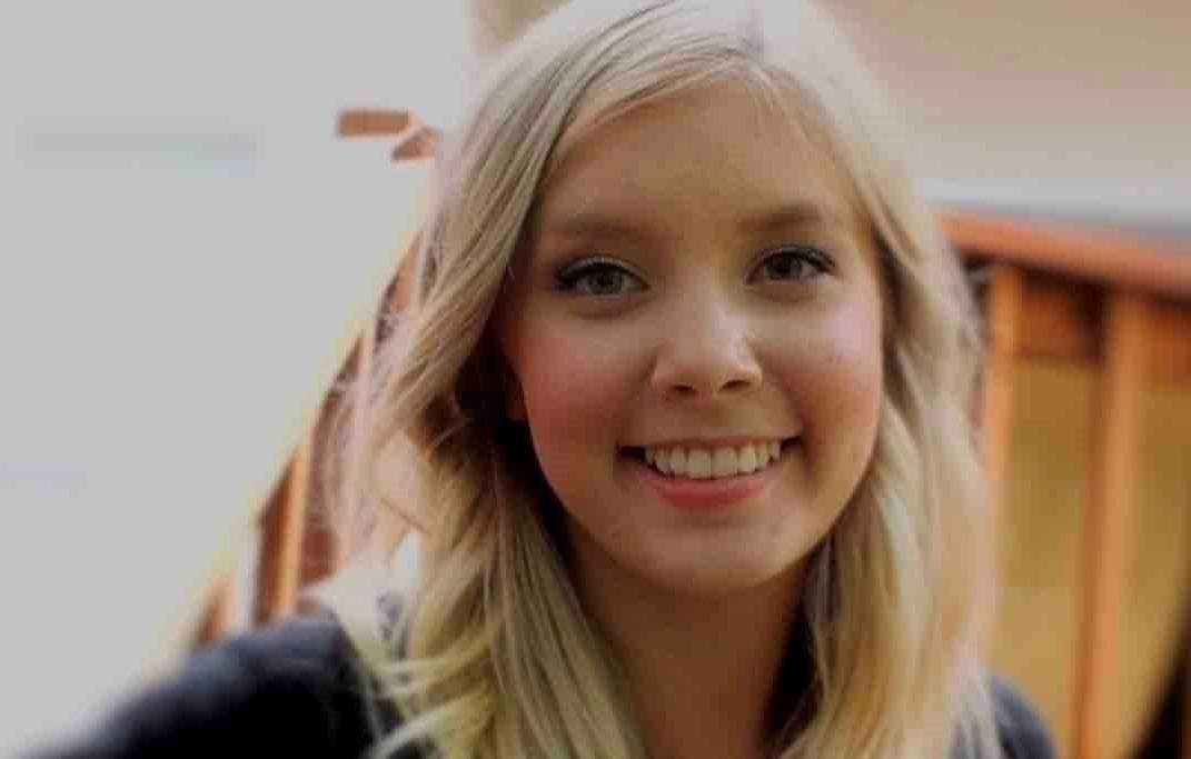 Caitlin Jensen smiles at the camera. She has long blonde hair and is wearing a dark top.