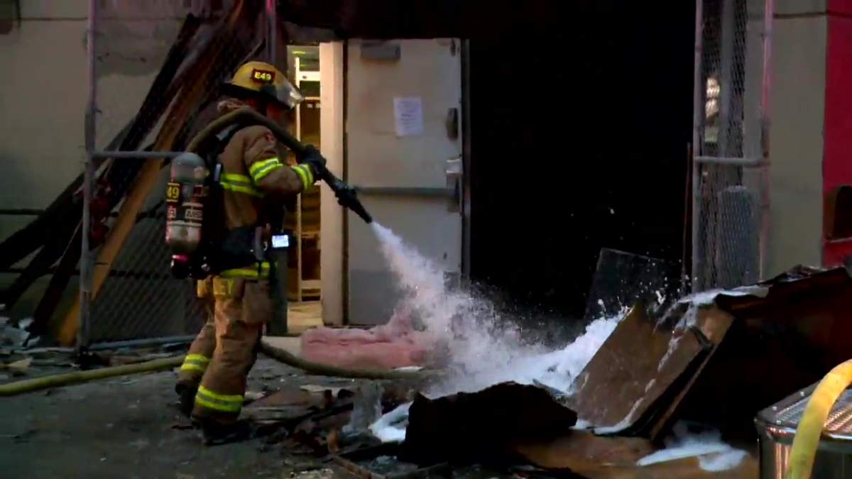A Calgary firefighter sprays water on damaged material from a building fire on the 800 block of 10th Avenue SW on July 3, 2022.
