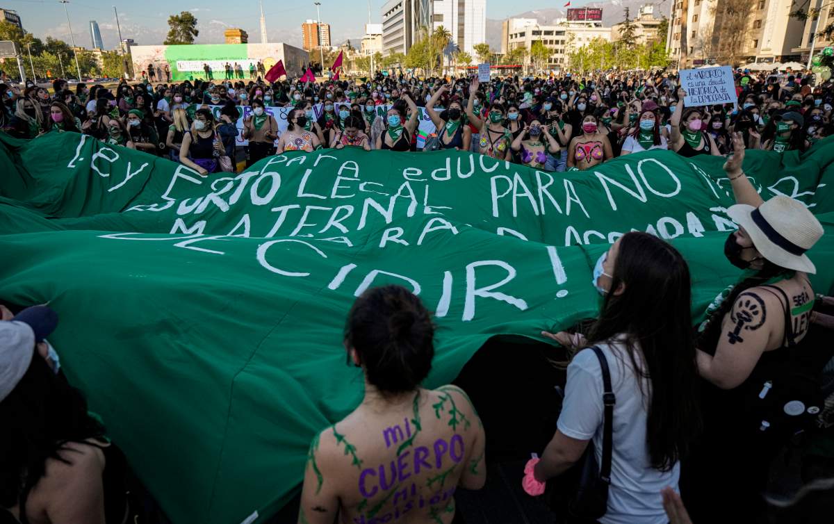 Abortion rights demonstrators march with a green banner in Chile.