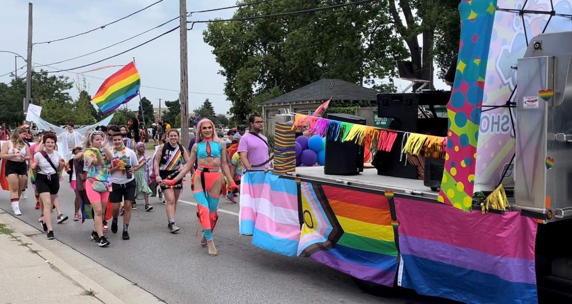 A group dances and cheers as they walk down Dundas St. in London's Pride Parade 2022. 