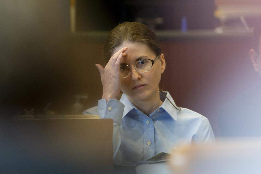 Sheila O'Leary in court, wearing glasses and a blue button down shirt.