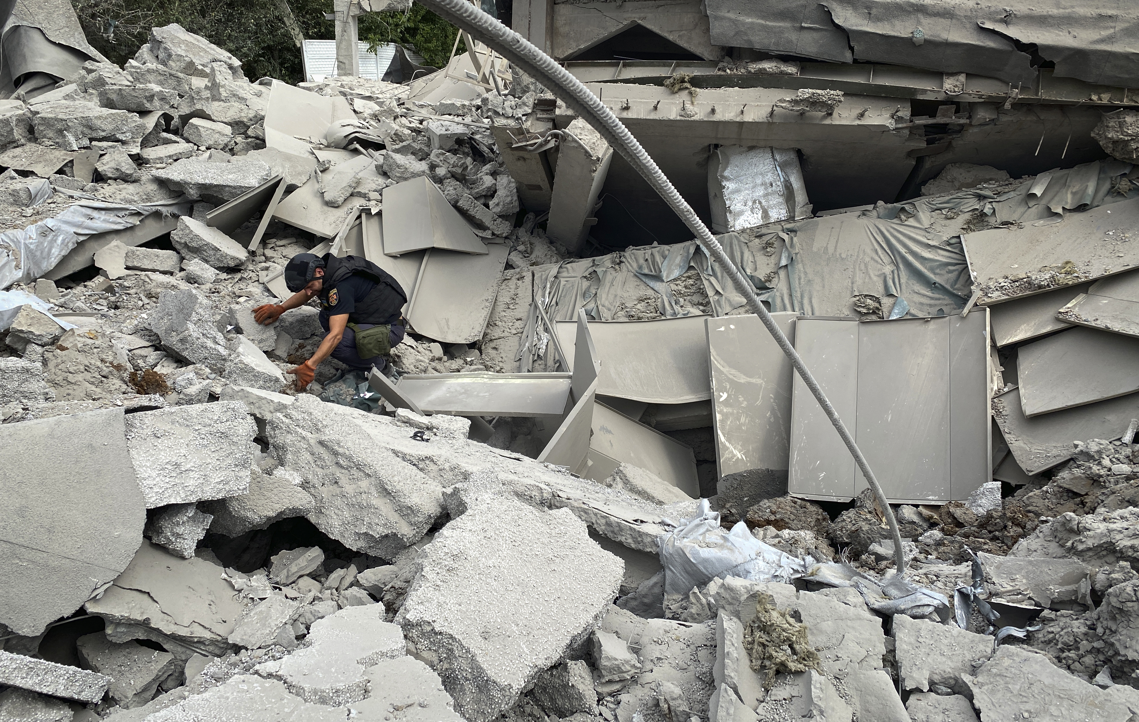 A Ukrainian serviceman inspects the rubble of the Employment Retraining Center that was destroyed by a Russian missile last night in Dergachi, on the outskirts of Kharkiv, Ukraine, Friday Aug. 26, 2022. (AP Photo/Sashko Brynza).