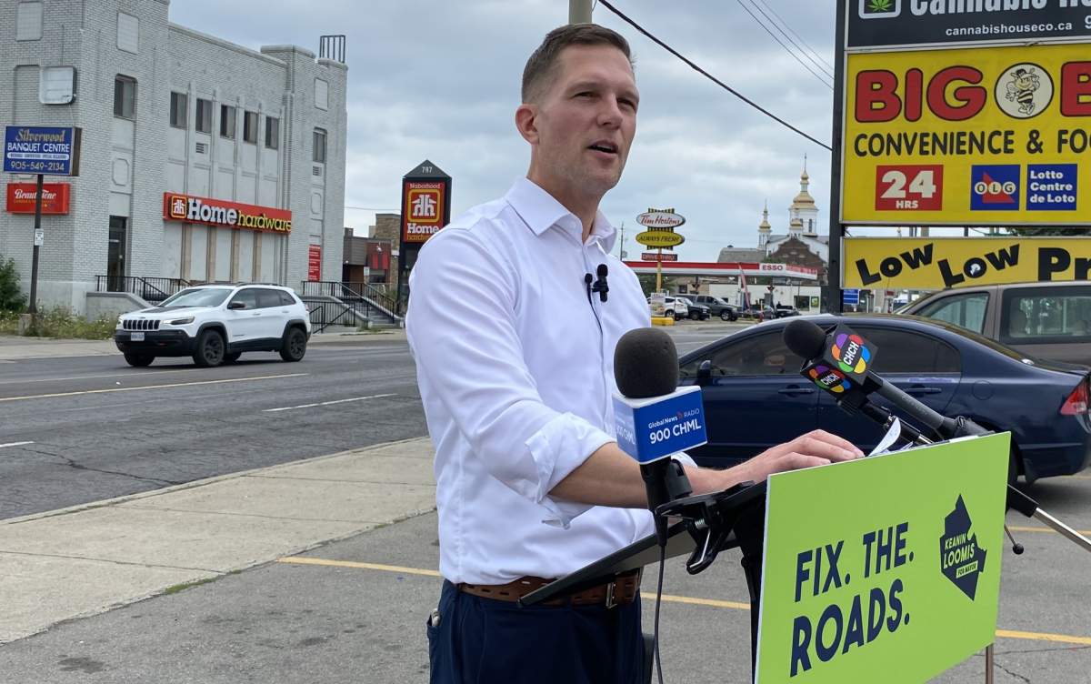 Keanin Loomis stands at a podium in front of Barton Street East.