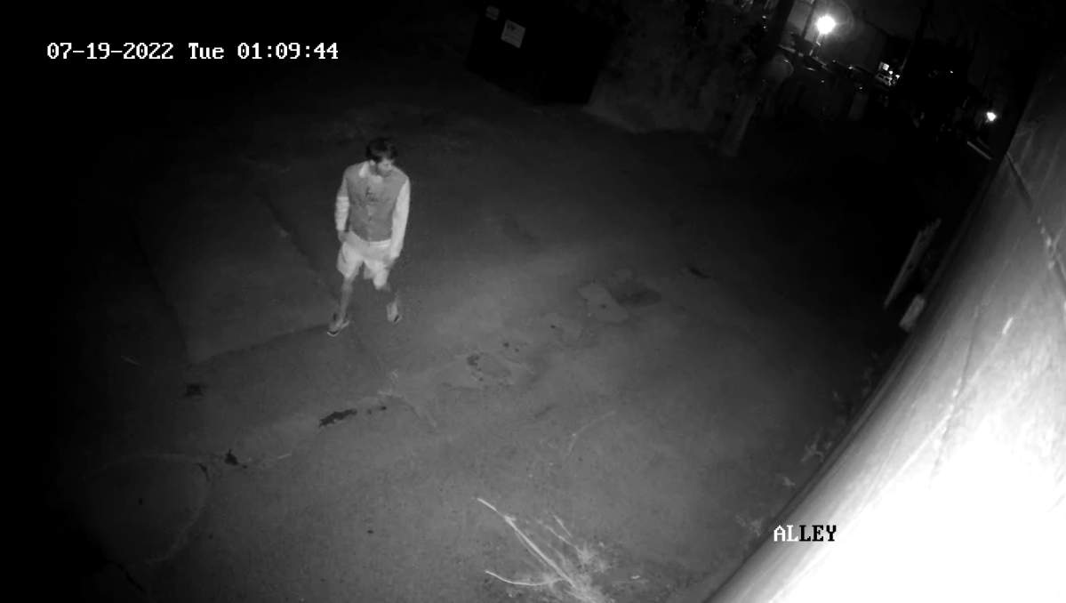 Surveillance footage still from July 19, 2022 showing a man writing on a wall in an alley in west Edmonton.