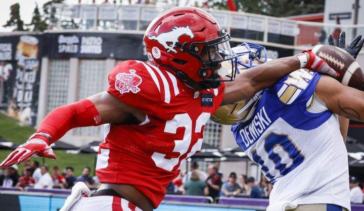 Winnipeg Blue Bombers receiver Nic Demski, right, tries to catch a pass as Calgary Stampeders defensive back Titus Wall grabs for him during first half CFL football action in Calgary, Saturday, July 30, 2022.