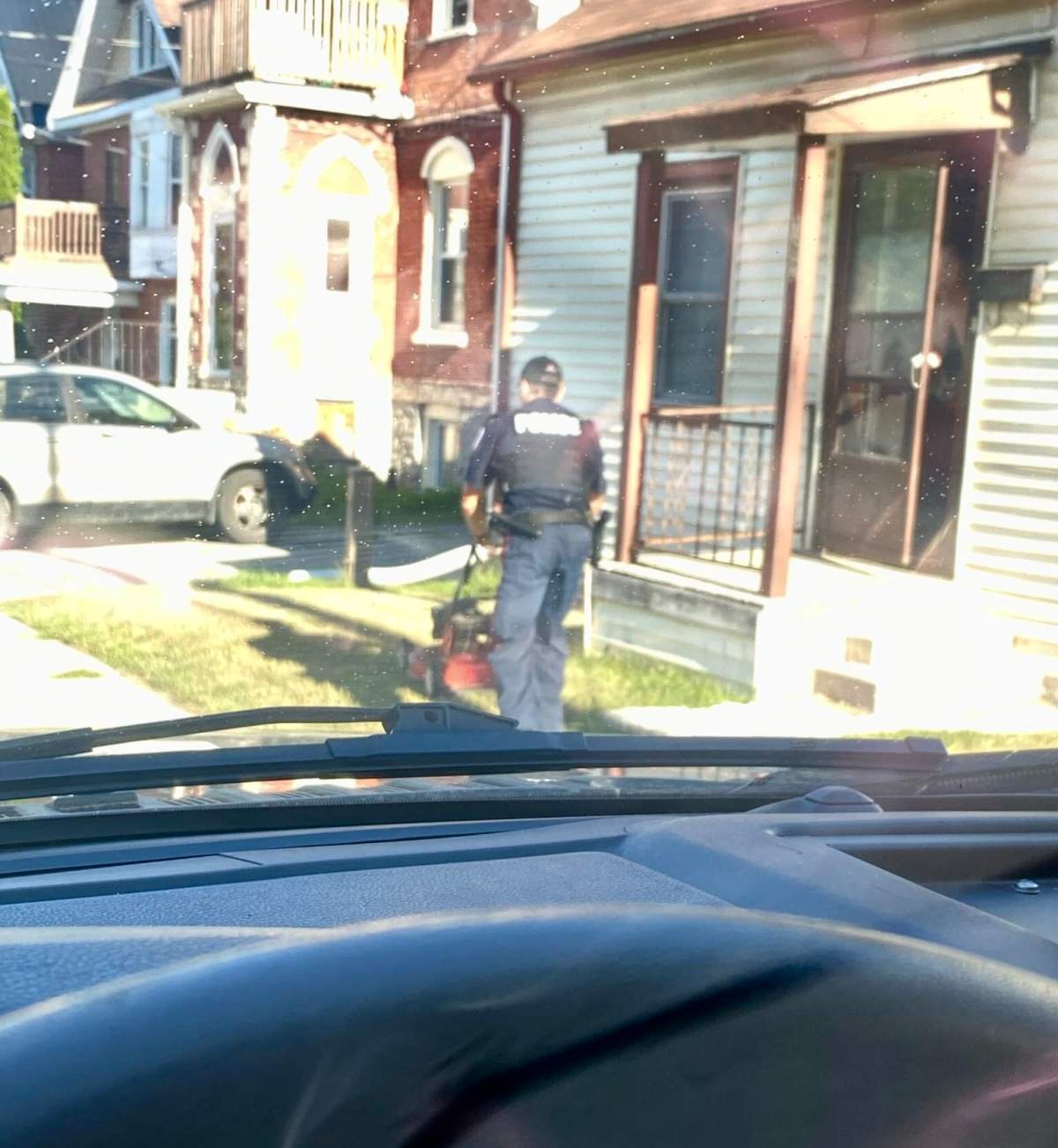 A Peterborough Police Service officer mows the lawn of a resident during a well-being check.