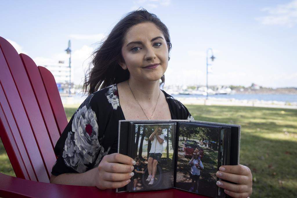 Alyssa Grocutt poses with pictures of her father Kevin who died when she was 11 years old while working at Suncor Energy Inc., in Kingston, Ont., on Wednesday, August 24, 2022. THE CANADIAN PRESS/Lars Hagberg.