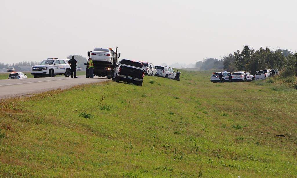 Police and investigators after Sanderson’s stolen car was shunted off the road. THE CANADIAN PRESS/Kelly Geraldine Malone