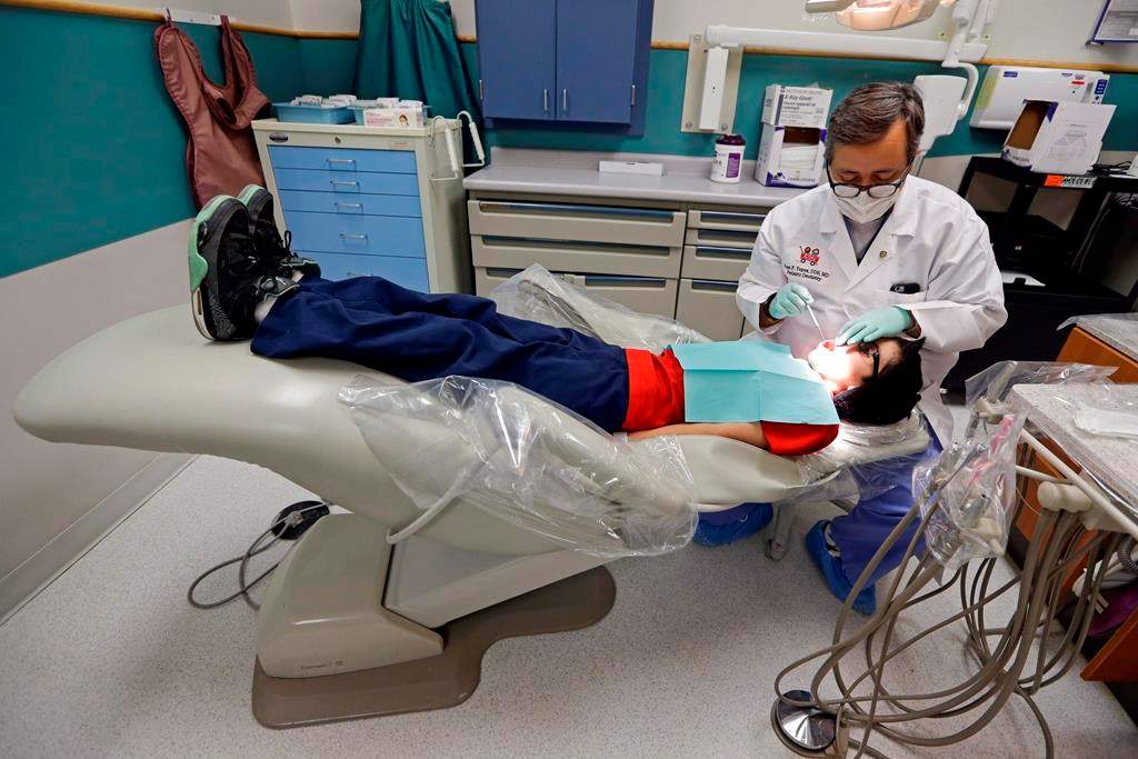 A dentist at the Riley Hospital for Children Department of Pediatric Dentistry, checks the teeth of Justin Perez, 11, during an office visit in Indianapolis, Friday, Jan. 22, 2016. University of Calgary associate economics professor Lindsay Tedds warns the federal dental benefit for children opens families up to the potential for "clawbacks" if they don't spend all the money on their kids' teeth.