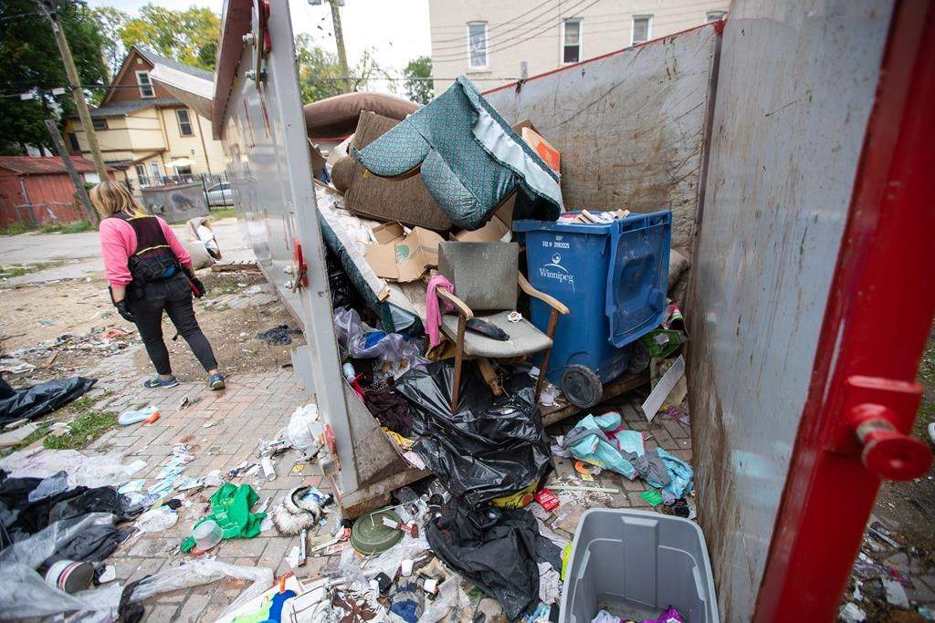 Angela Klassen Janeczko walks by a newly installed and overflowing garbage container behind an apartment building during a Bear Clan patrol in Winnipeg's West Broadway neighbourhood on Sunday, Sept. 18, 2022. 