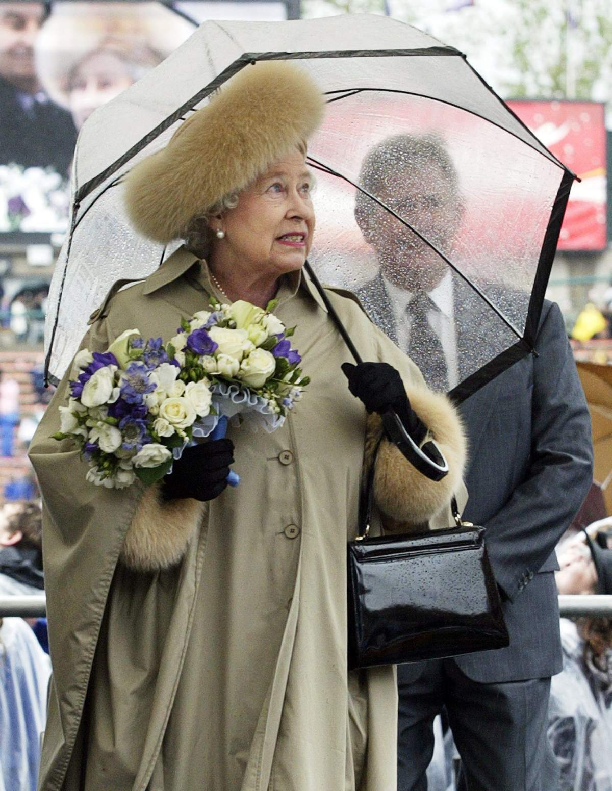 Alberta Premier Ralph Klein follows Queen Elizabeth II onto the seating platform during rainy Alberta centennial celebrations at Commonwealth Stadium Monday, May 23, 2005 in Edmonton. (CP PHOTO/Paul Chiasson)
