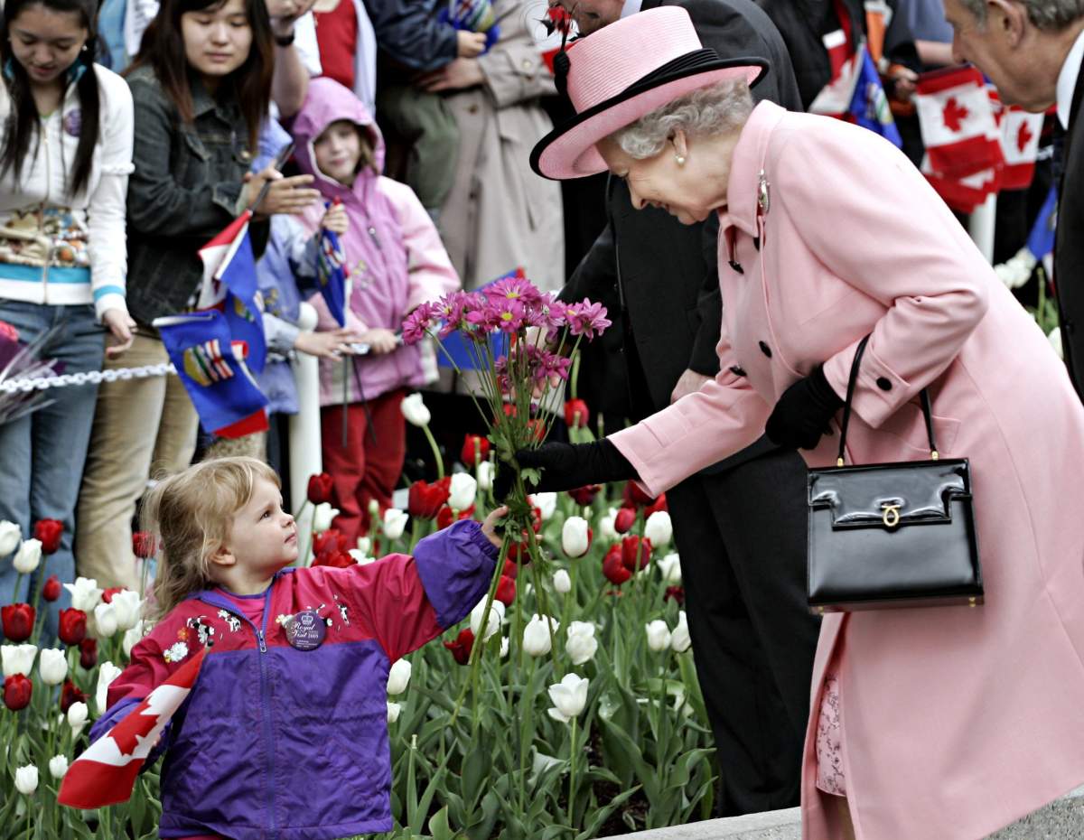 Queen Elizabeth II receives flowers from a young girl as she leave the Alberta Legislature in Edmonton, Tuesday, May 24, 2005. The Queen is in Alberta to celebrate the province’s centennial.
