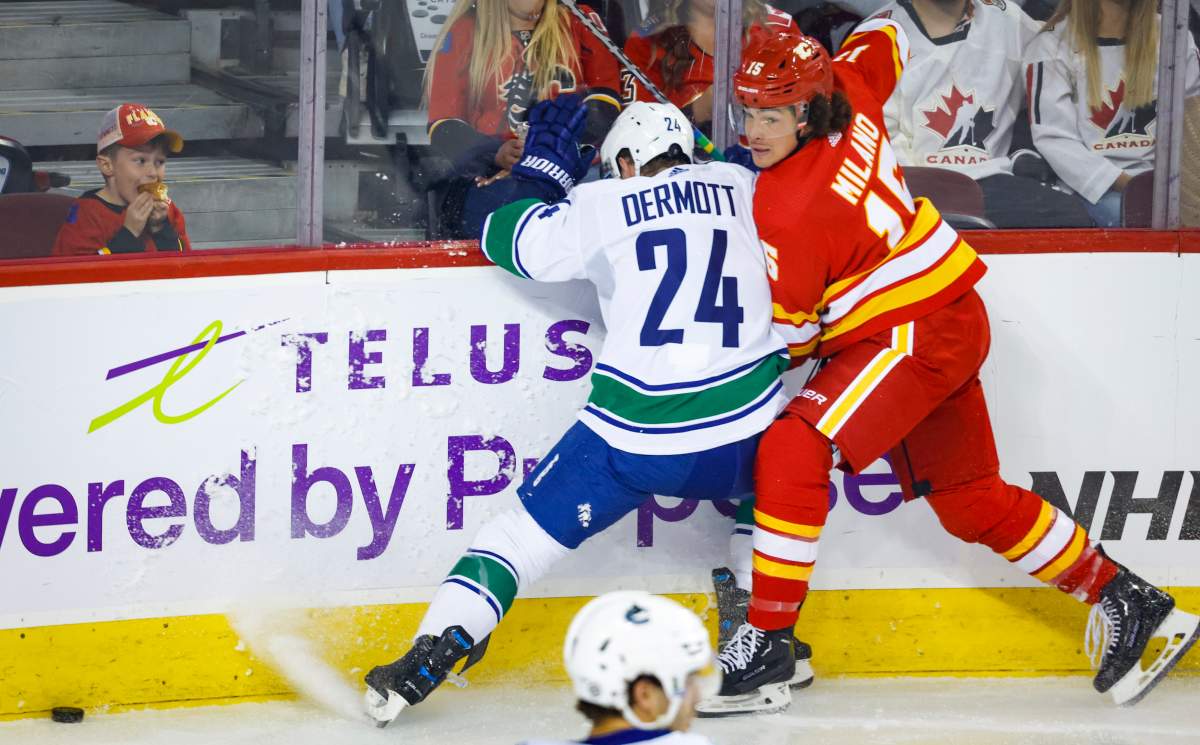Vancouver Canucks defenceman Travis Dermott, left, checks Calgary Flames forward Sonny Milano during first period NHL pre-season hockey action in Calgary, Alta., Sunday, Sept. 25, 2022.