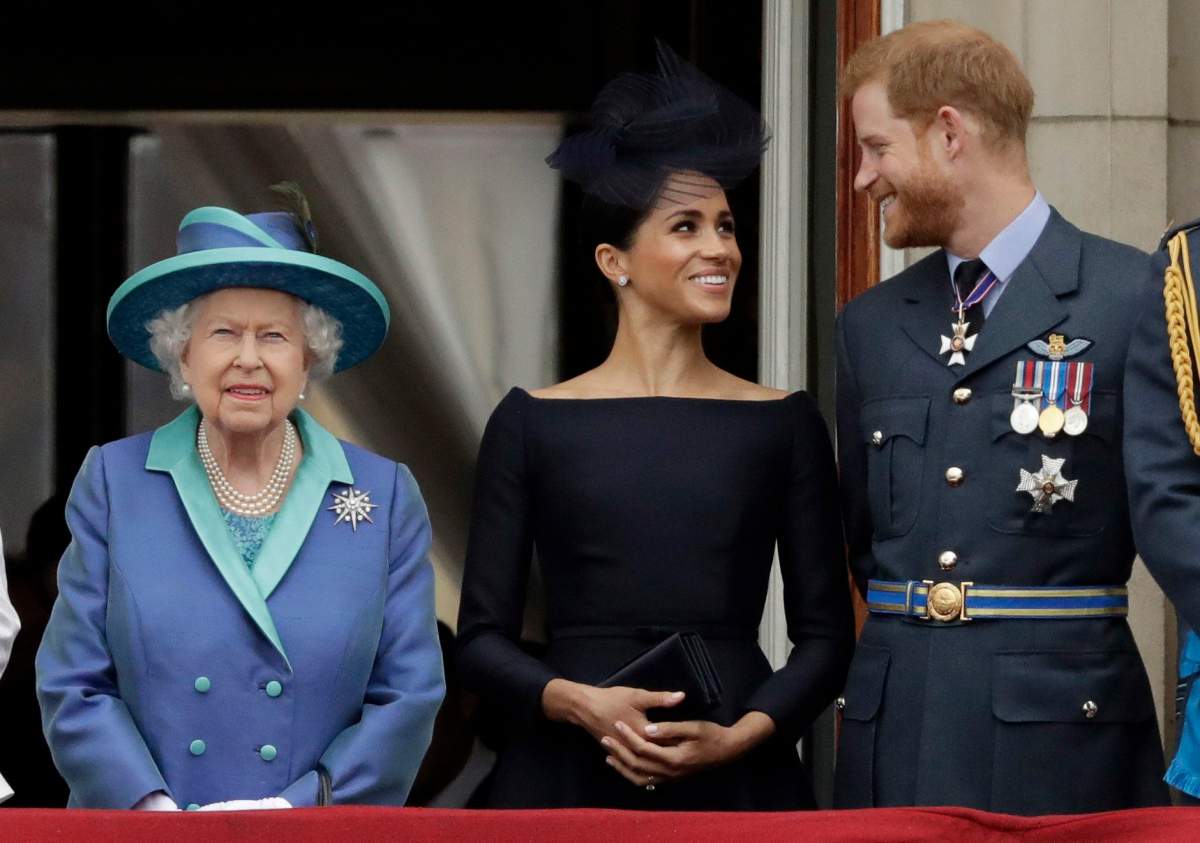 In this Tuesday, July 10, 2018 file photo Britain’s Queen Elizabeth II, and Meghan the Duchess of Sussex and Prince Harry watch a flypast of Royal Air Force aircraft pass over Buckingham Palace in London.