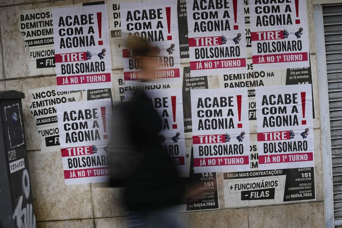 A woman walks past signs that read in Portuguese: “End the Agony, Bolsonaro Out,” in Rio de Janeiro, Brazil, Friday, Sept. 30, 2022. Brazil’s general elections are scheduled for Oct. 2. (AP Photo/Matias Delacroix)