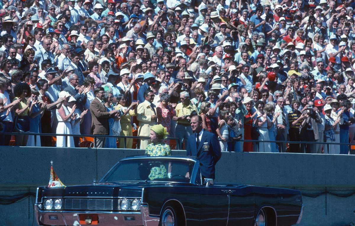 Queen Elizabeth ll and Prince Philip, Duke of Edinburgh ride in an open car past spectators in the stands as they arrive to open the Commonwealth Games on August 03, 1978 in Edmonton, Canada.