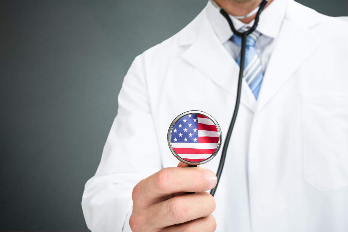 A stock images shows a doctor holding a stethoscope printed with the American flag.