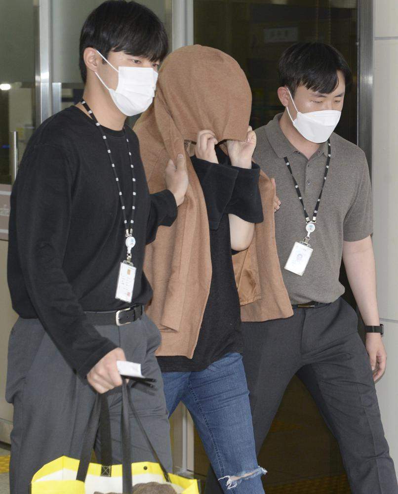 A woman, center, leaves to the Seoul Central District Prosecutors' Office at Ulsan Jungbu police station in Ulsan, South Korea, Thursday, Sept. 15, 2022. The woman was arrested in South Korea on Thursday on two murder charges from New Zealand, where the bodies of two long-dead children were found last month in abandoned suitcases, authorities said.