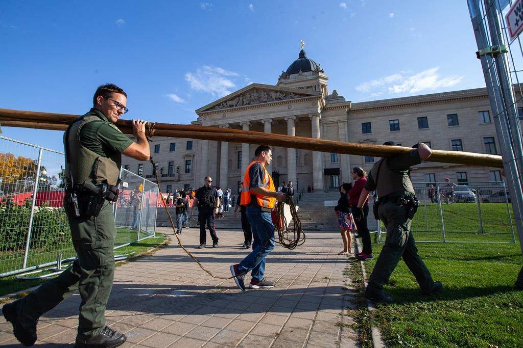 Legislative security officers, conservation officers supported by Winnipeg police, move to evict a camp on the north side of the Manitoba legislature grounds in Winnipeg, Tuesday, Oct. 4, 2022. Police say four men and one woman are charged with obstructing a peace officer and occupying a structure in the legislative precinct. THE CANADIAN PRESS/Daniel Crump.