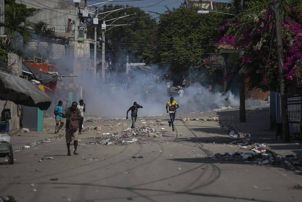 Protesters are dispersed by tear gas thrown by the police during a demonstration to demand the resignation of Prime Minister Ariel Henry in the Petion-Ville area of Port-au-Prince, Haiti, Monday, Oct. 3, 2022. (AP Photo/Odelyn Joseph).