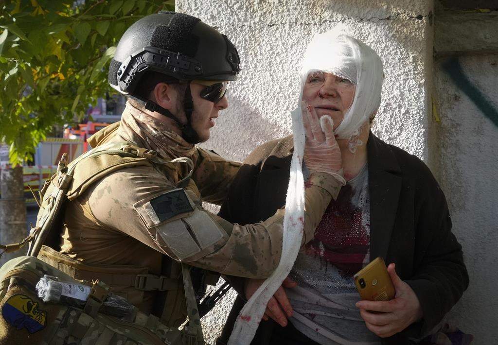 An injured woman receives medical treatment at the scene of Russian shelling, in Kyiv, Ukraine, Monday, Oct. 10, 2022. Prime Minister Justin Trudeau condemned Russia's latest attacks on Ukraine as the country unleashed a lethal barrage of strikes against multiple Ukrainian cities on Monday, including downtown Kyiv where at least six people were killed. THE CANADIAN PRESS/AP/Efrem Lukatsky.