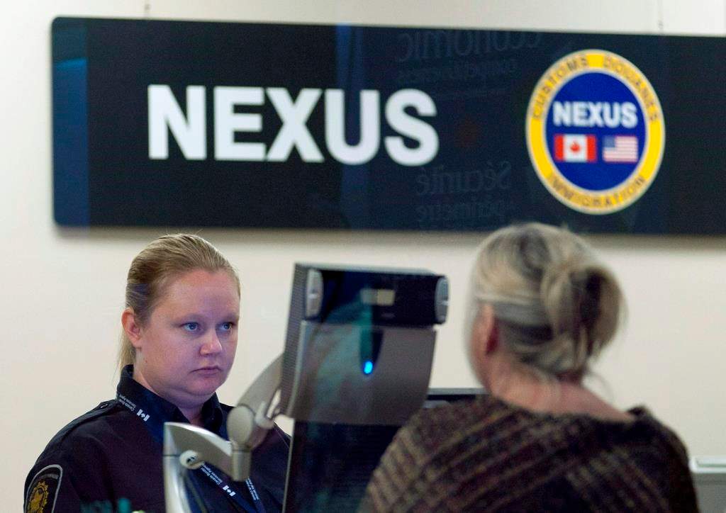 A Canada Border Services Agency officer speaks with a traveller at the Nexus office at the airport in Ottawa, Tuesday, May 8, 2012. 