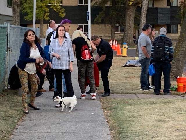 Claudia Troncoso, her dog, and other residents outside after fire damaged an apartment building at 10368 92 St. in Edmonton's Boyle Street neighbourhood on Monday, Oct. 17, 2022.