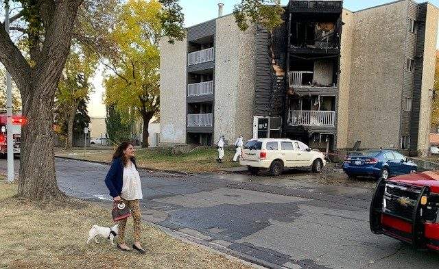 Claudia Troncoso, her dog, and other residents outside after fire damaged an apartment building at 10368 92 St. in Edmonton's Boyle Street neighbourhood on Monday, Oct. 17, 2022.