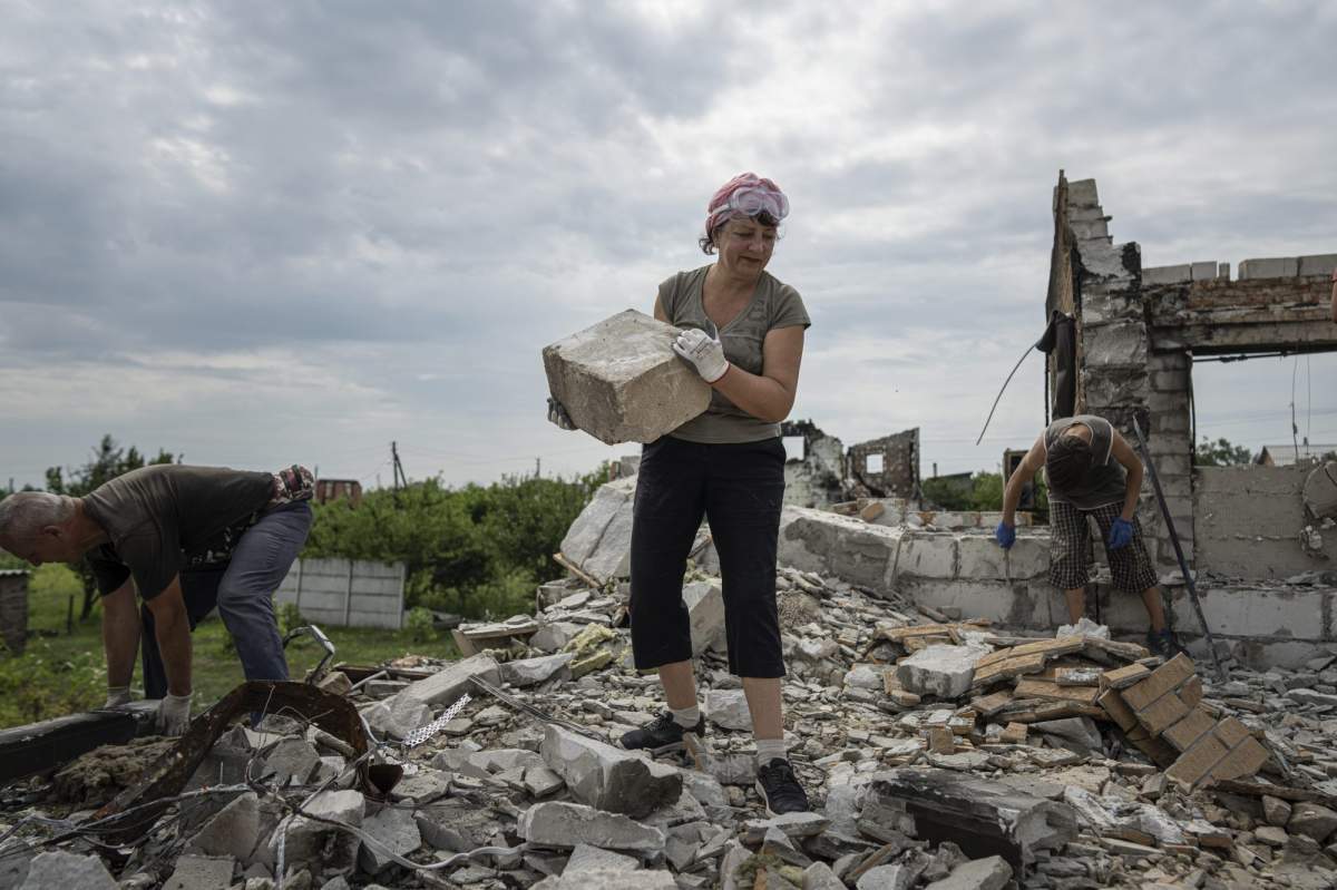 Volunteers clear the rubble from a home near Chernihiv, Ukraine that was destroyed by Russian bombs on Saturday, Aug. 13, 2022. Residents in many heavily-damaged areas in Ukraine have set up their own initiatives to rebuild homes before the winter as international organizations rush aid to Ukraine to help with the reconstruction effort.