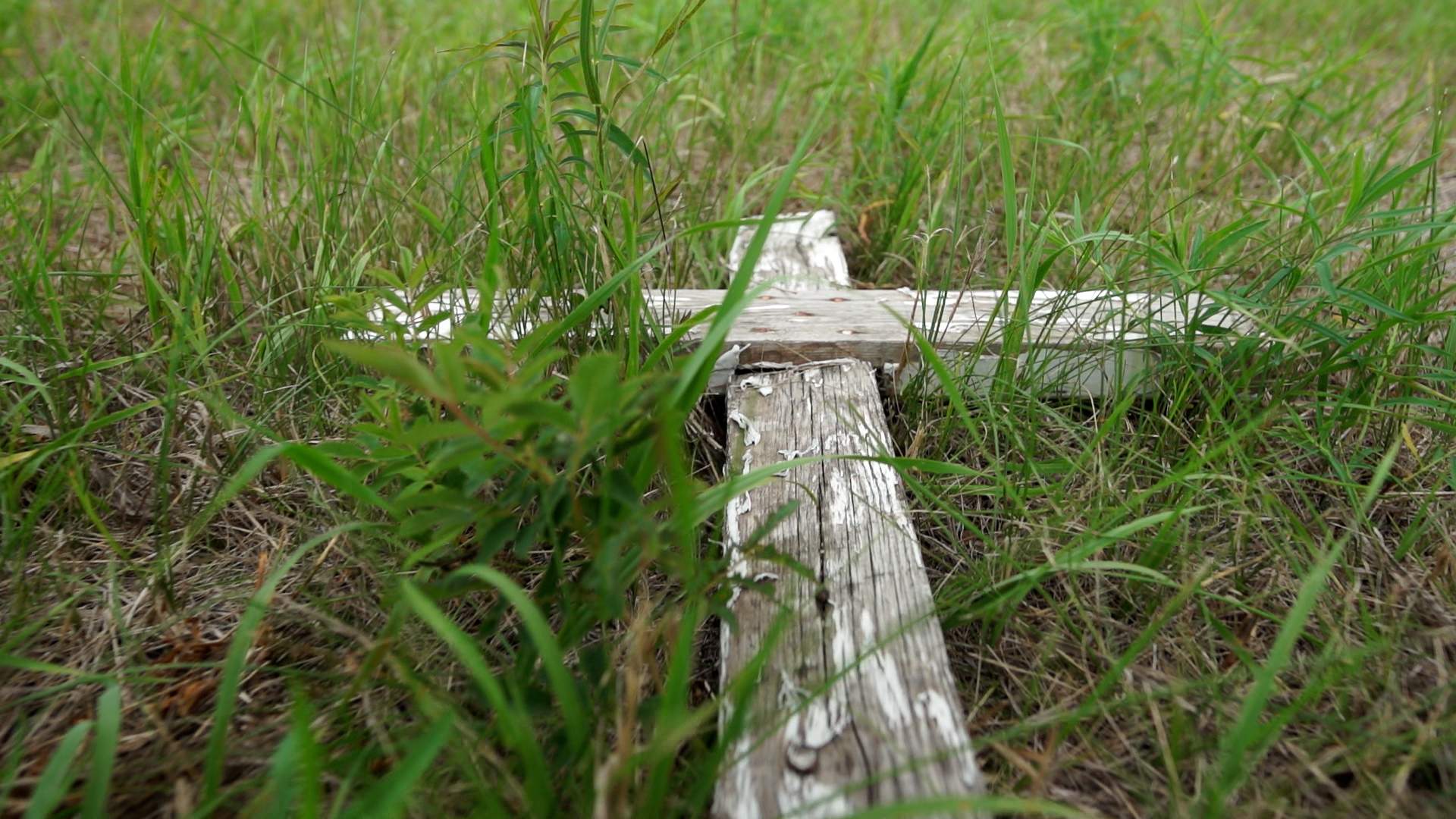 A wooden cross lays flat on the ground in the North Hill Burial Ground north of the former Brandon Residential School site.