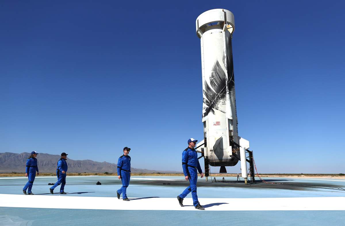 Blue Origin vice president of mission and flight operations Audrey Powers, Star Trek actor William Shatner, Planet Labs co-founder Chris Boshuizen and Medidata Solutions co-founder Glen de Vries walk across a landing pad.