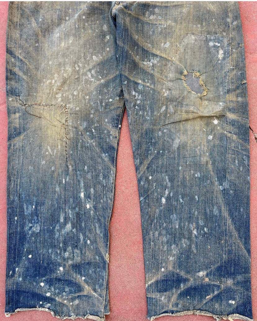 The 1800s Levi's jeans, facing forward. There is white wax stains on the fabric.