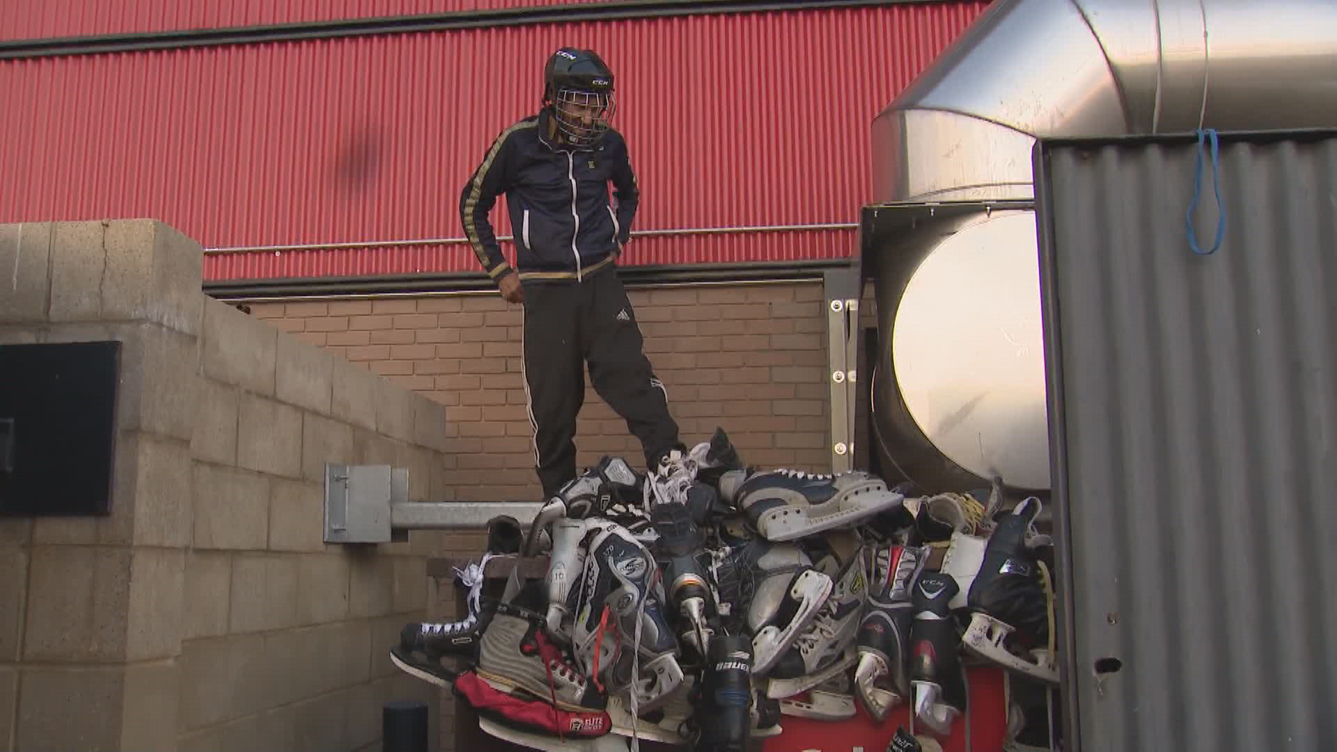Jonathan Battle surveys pile of hockey gear by garbage dumpster.
