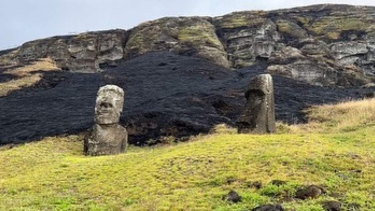Two moai in front of a scorched hill.