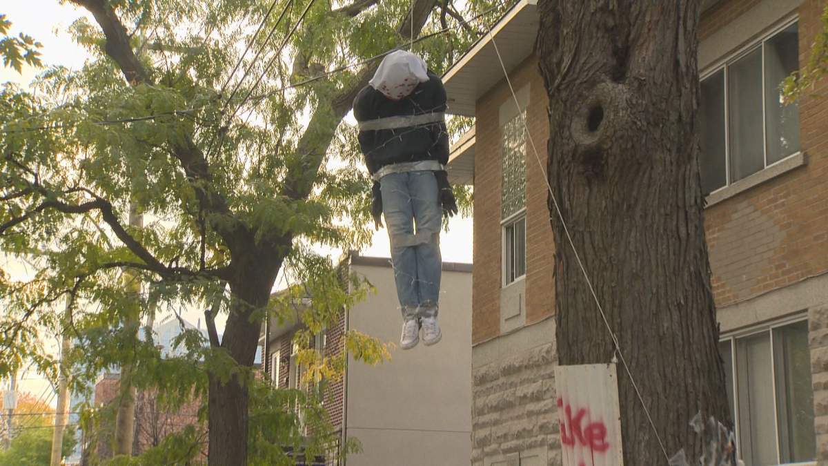A mannequin hangs from a noose in a tree over the sidewalk in Ahuntsic-Cartierville.