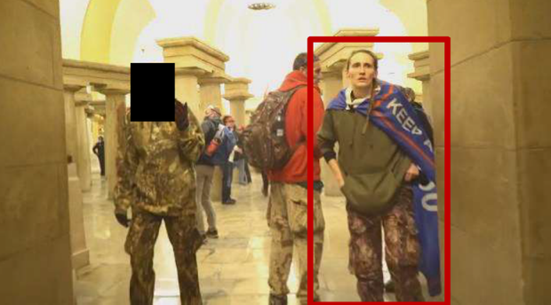 Kristi Munn in the U.S. Capitol building. She is wearing camouflage and a Trump banner around her neck.
