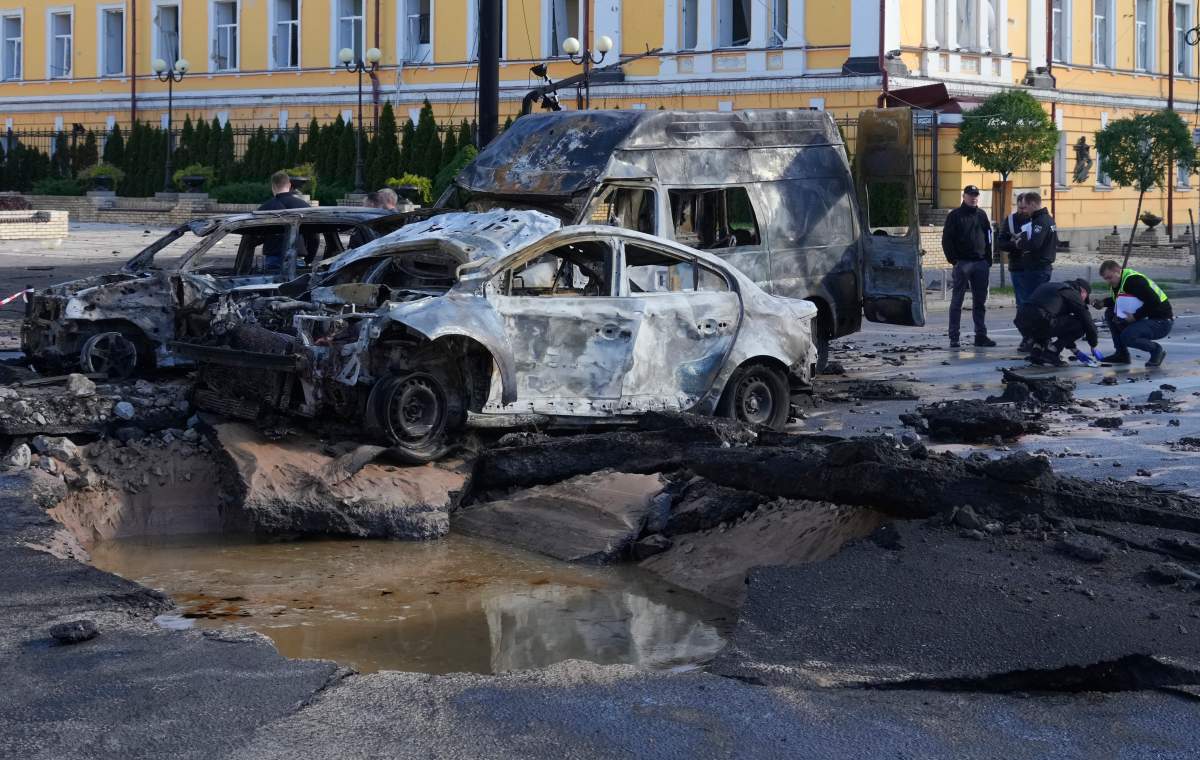 Damaged cars are seen at the scene of Russian shelling, in Kyiv, Ukraine, Monday, Oct. 10, 2022. Explosions on Monday rocked multiple cities across Ukraine, including missile strikes on the capital Kyiv for the first time in months. (AP Photo/Efrem Lukatsky)