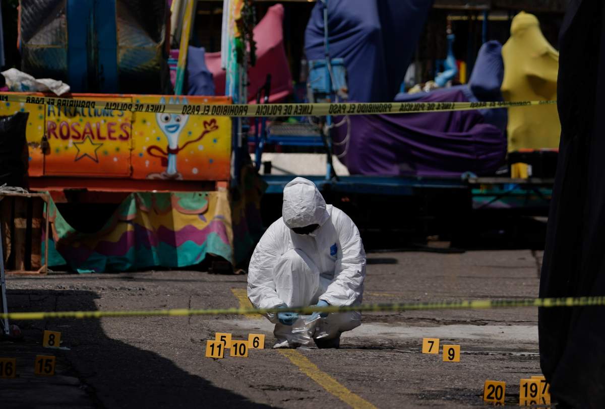 A forensics investigator works the scene of a massive shootout in San Miguel Totolapan, Mexico, Thursday, Oct. 6, 2022. A drug gang burst into the town hall and shot to death 20 people, including a mayor and his father, officials said Thursday.