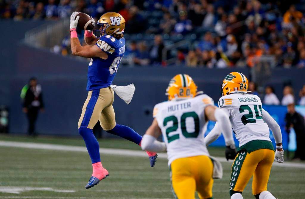 The Winnipeg Blue Bombers’ Dalton Schoen (83) catches a pass as the Edmonton Elks’ Scott Hutter (20) and Jeff Richards (24) defend during first-half CFL action in Winnipeg Saturday, Oct. 8, 2022.