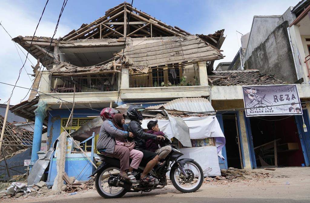 People ride a motorbike past a building damaged in Monday’s earthquake in Cianjur, West Java, Indonesia, Tuesday, Nov. 22, 2022.