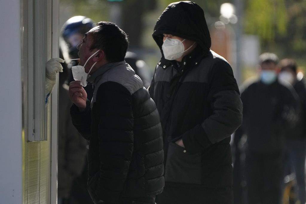 A man has his throat swabbed for a COVID-19 test at a testing site near the site of last weekend’s protest in Beijing, Wednesday, Nov. 30, 2022.