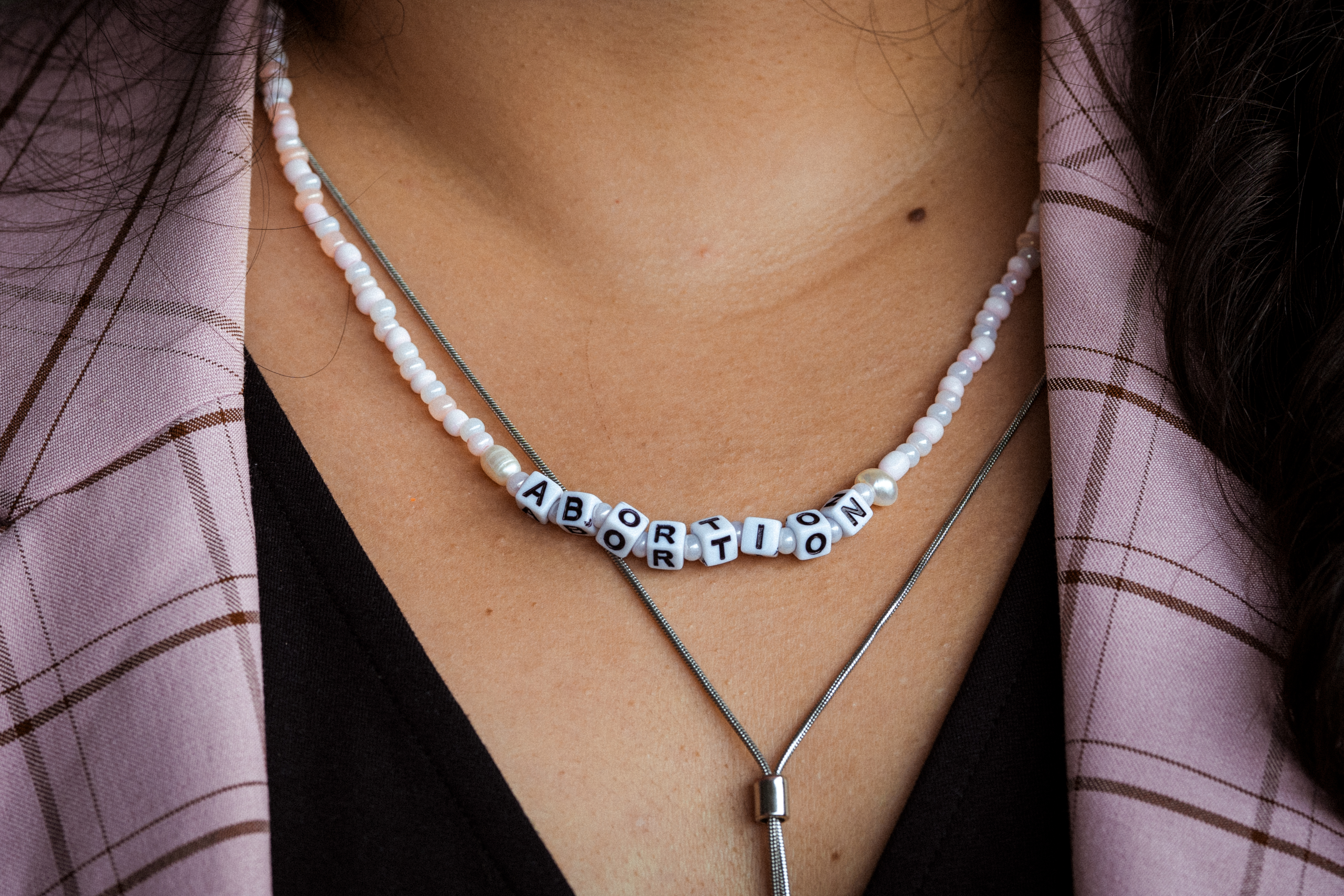 A woman who works at an Ontario abortion clinic wears a beaded necklace spelling "abortion"