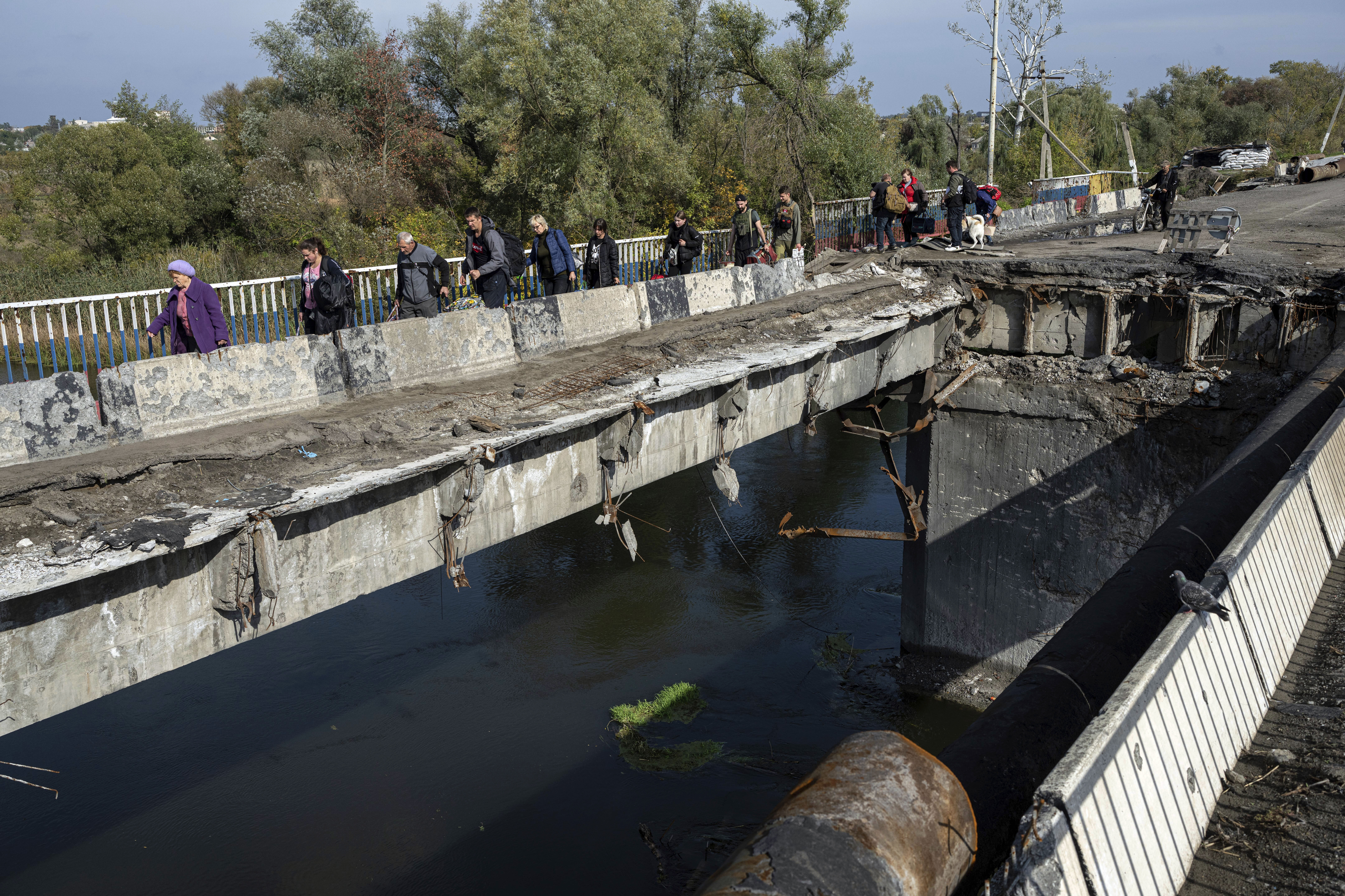 Civilians cross damaged bridge over Oskil River during the evacuation of Kupiansk, Ukraine, on Oct. 1. (AP Photo/Evgeniy Maloletka)
