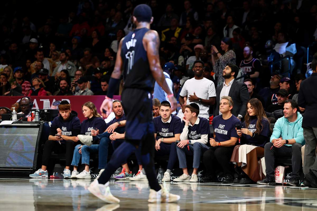 Kyrie Irving passes the courtside spectators wearing 'Stop Antisemitism' T-shirts.