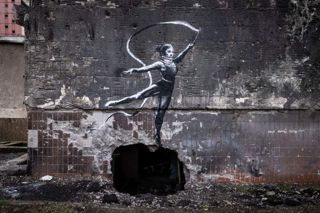 Graffiti of a woman in a leotard and a neck brace waving a ribbon is seen on the wall of a destroyed building in Irpin on November 11, 2022 in Kyiv Region, Ukraine.