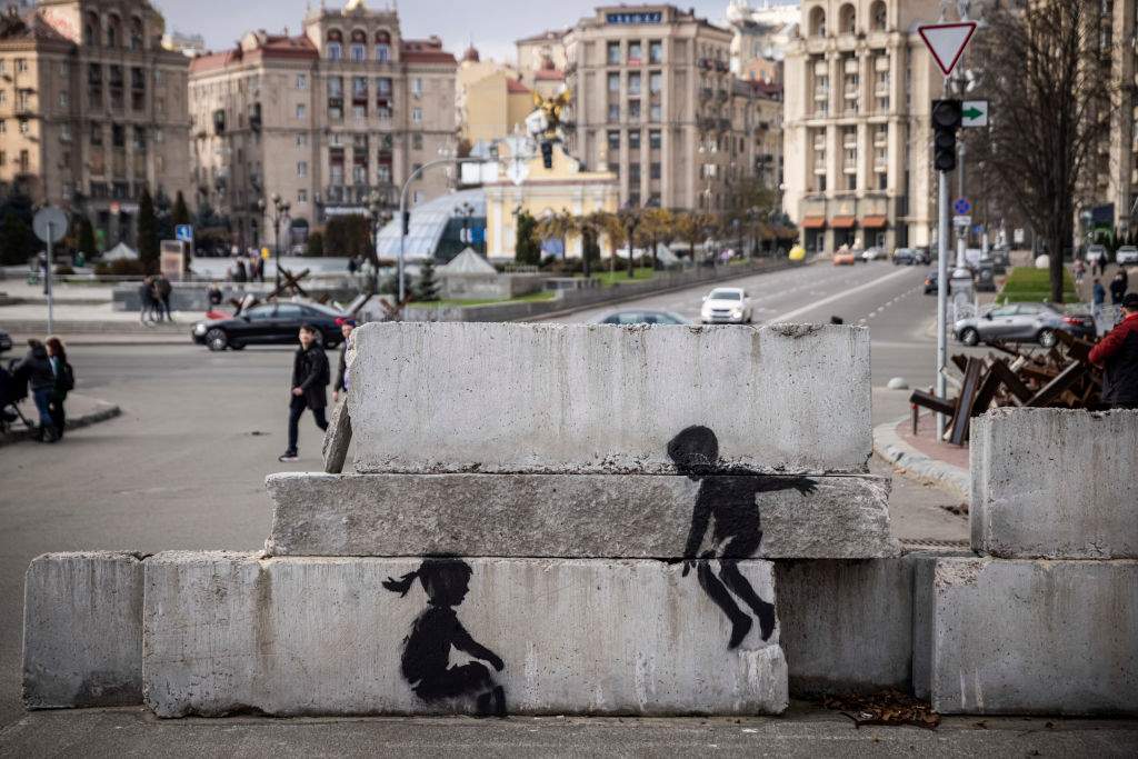 Street art of two children is painted on blocks of concrete in Independence Square on November 12th 2022 in Kyiv Region, Ukraine. A military roadblock made of steel girders, often referred to as hedgehogs, used to sit between the children, giving the appearance that the children were playing on a seesaw.