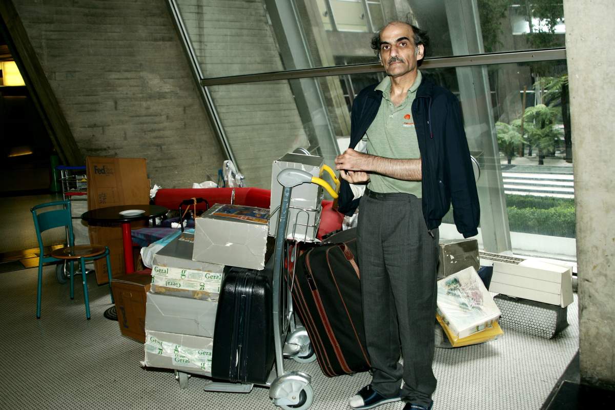 Mehran Karimi Nasseri beside his possessions on trolleys.