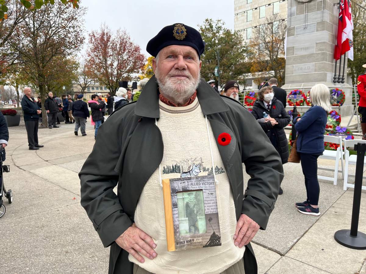 Douglas Small poses in front of the Cenotaph in Victoria Park. Hanging around his neck is a photo of his father Fred "Freddy" Small, who served in the Royal Canadian Navy during the Second World War.