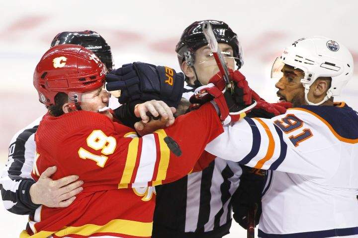 Referees try to break it up as Edmonton Oilers’ Evander Kane, right, mixes it up with Calgary Flames’ Matthew Tkachuk during second period NHL hockey action in Calgary, Alta., Monday, March 7, 2022.